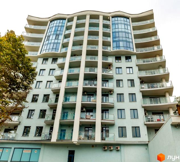 Житловий комплекс Santorini. Висотна будівля з балконами та скляними перилами. На першому поверсі розташовані комерційні приміщення.