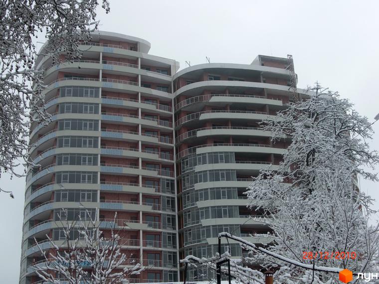 Житловий комплекс Ланжерон з сучасним фасадом та балконами, оточений засніженими деревами та прибудинковою територією.