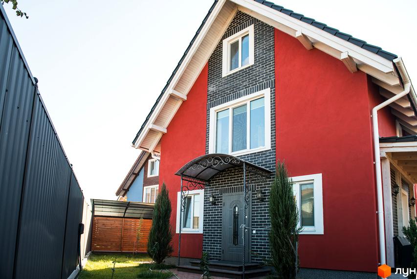 Котеджне містечко Osocor Scandi House: червоний будинок з темно-сірою цегляною обробкою та білими вікнами. Перед будинком зелений газон та хвойні дерева.