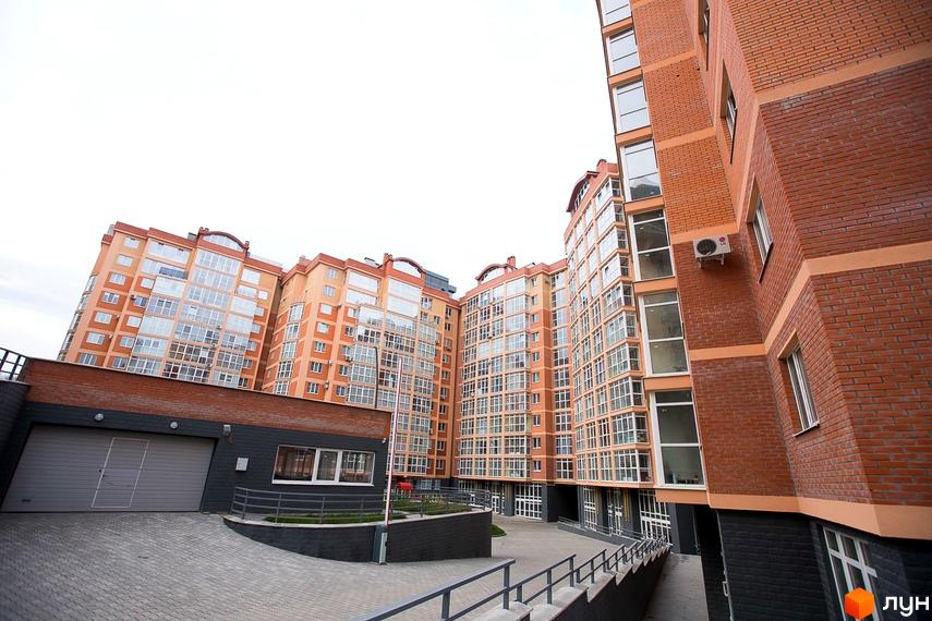 Багатоповерхові цегляні будинки ЖБК Перспектива з великими вікнами та балконами. Вид на внутрішній двір з підземним паркінгом та вимощеною територією.