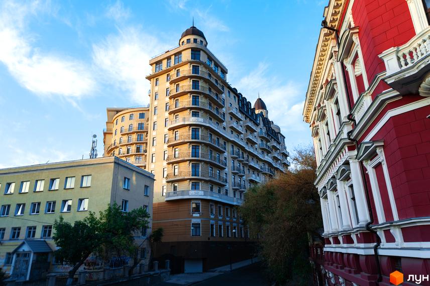 Житловий комплекс Наследие Дерибаса з сучасним фасадом та прибудинковою територією, оточений іншими будівлями.