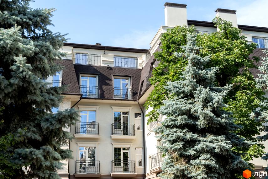 Фасад житлового комплексу CHELSEA Club House з вікнами та балконами, оточений зеленню дерев. Зовнішній вигляд будівлі та прибудинкова територія.