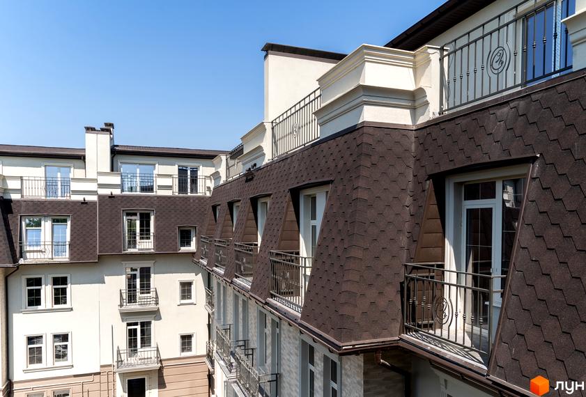 Зовнішній вигляд будинку ЖК CHELSEA Club House з коричневим дахом та балконами. Фото фасаду новобудови з вікнами та балюстрадами.