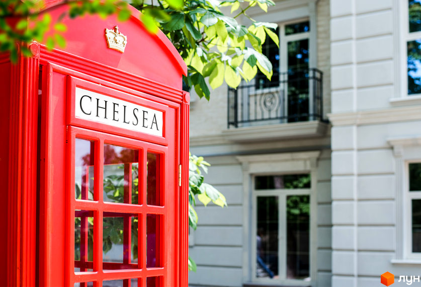 Житловий комплекс CHELSEA Club House в Лондоні. Червона телефонна будка на фоні білої будівлі з балконом та деревами.