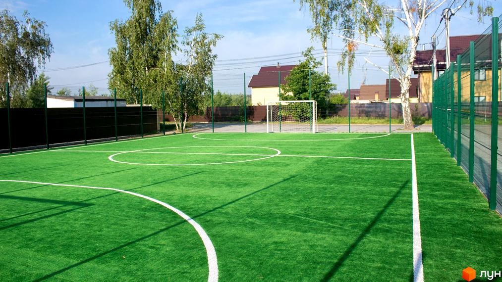 Футбольне поле з штучним покриттям на території Котеджного містечка КМ Вишневий хуторок. Зелена трава, розмітка, ворота та огорожа.