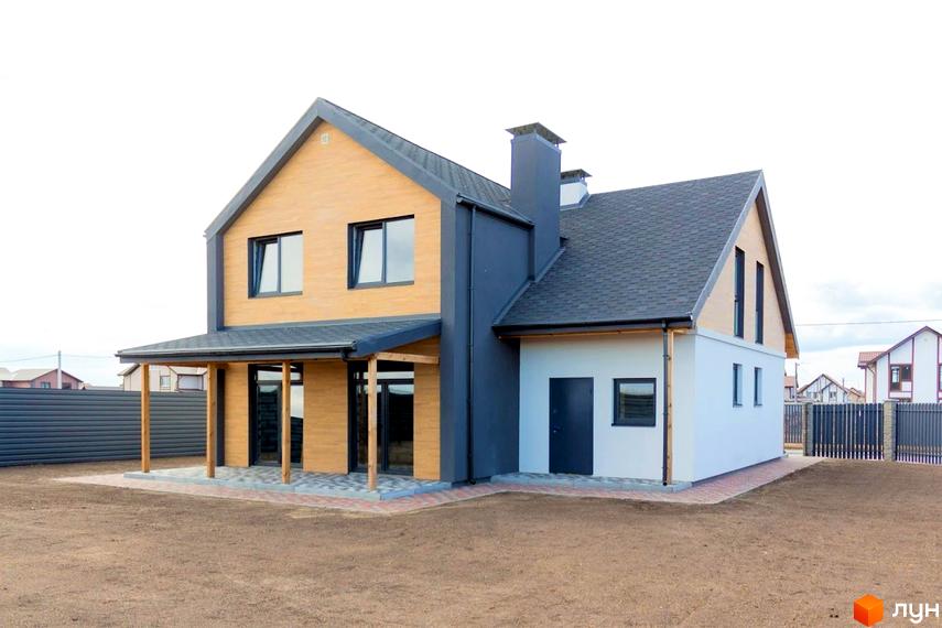 Будинок у Котеджному містечку Нова Олександрівка з фасадом зі світлого дерева та темно-сірих панелей, чорною покрівлею. Поруч ґрунтова ділянка та вимощена тераса.