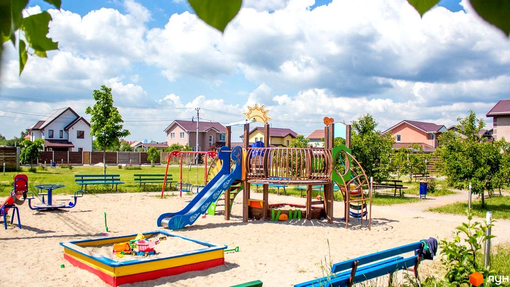 Котеджне містечко Нова Олександрівка: двоповерхові будинки з коричневими дахами. На території розташований дитячий майданчик з ігровим комплексом та пісочницею.