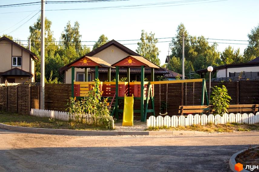 На фото зображено будинок з дитячим майданчиком на території. Поруч розташовано Котеджне містечко Лісове озеро.