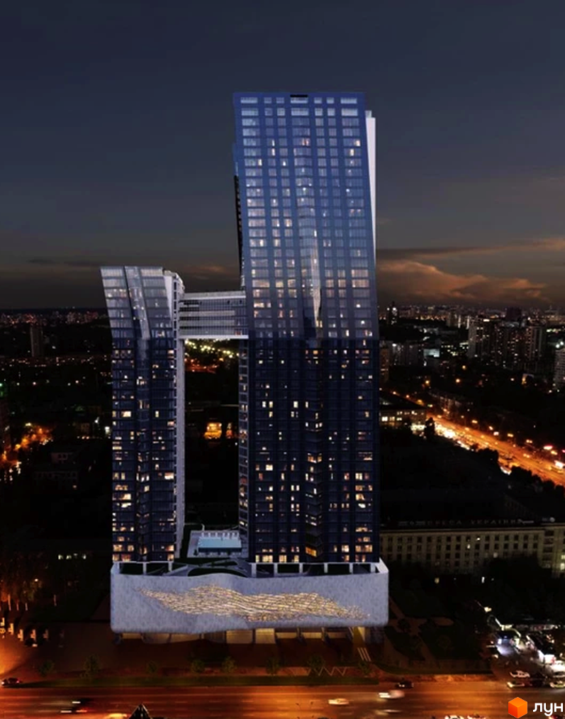Висотна будівля БФК 50Avenue з панорамними вікнами та мостом між вежами на тлі нічного міста. На першому поверсі розташована велика тераса.