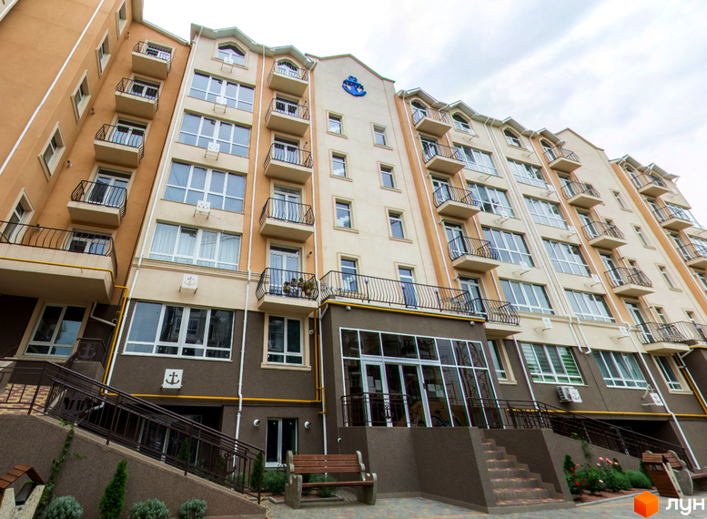 Житловий комплекс Якоря. Багатоповерховий будинок з балконами та панорамними вікнами. Біля будинку розташовані сходи, лавочки та зелені насадження.