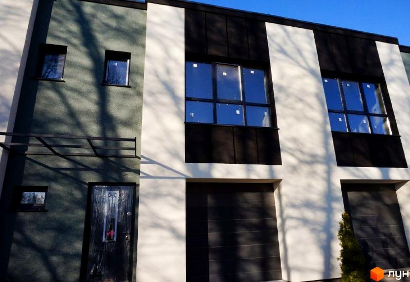 Фасад таунхауса Престиж з вертикальними секціями сірого, білого та чорного кольорів, чорними вікнами та гаражними воротами. На будинку видно тіні від дерев.