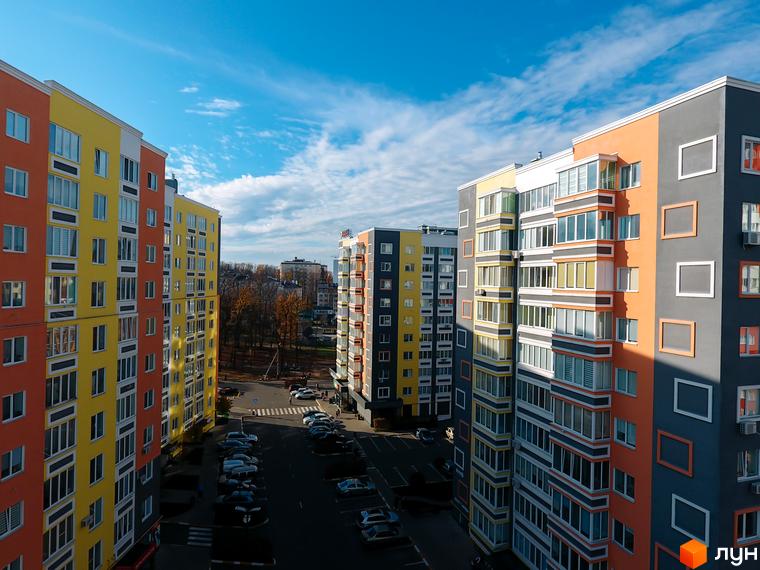 Високі будинки ЖК Синергія-2 з яскравими фасадами. На території комплексу є парковка для автомобілів.