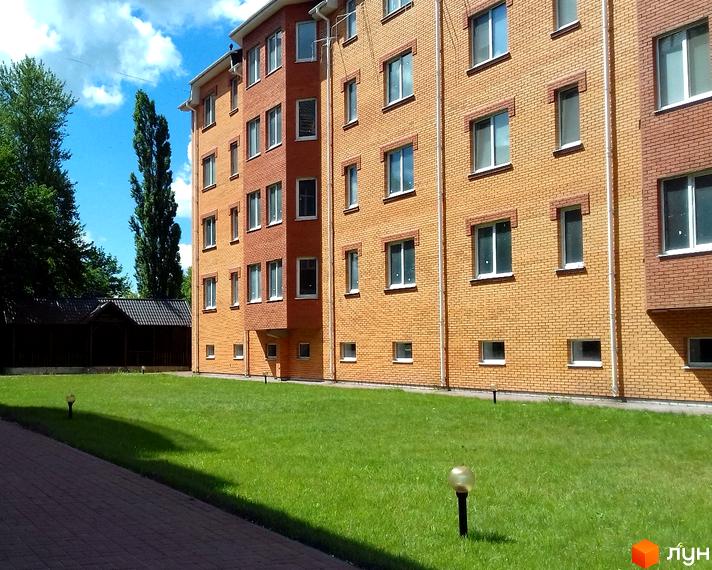 Цегляний багатоповерховий будинок з великими вікнами та доглянутою прибудинковою територією з газоном та ліхтарями. ЖК на вул. Полковника Гегечкорі (1905 року), 1в.