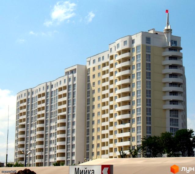 Житловий комплекс Тирас з сучасною архітектурою та балконами. Прибудинкова територія озеленена деревами та газонами.