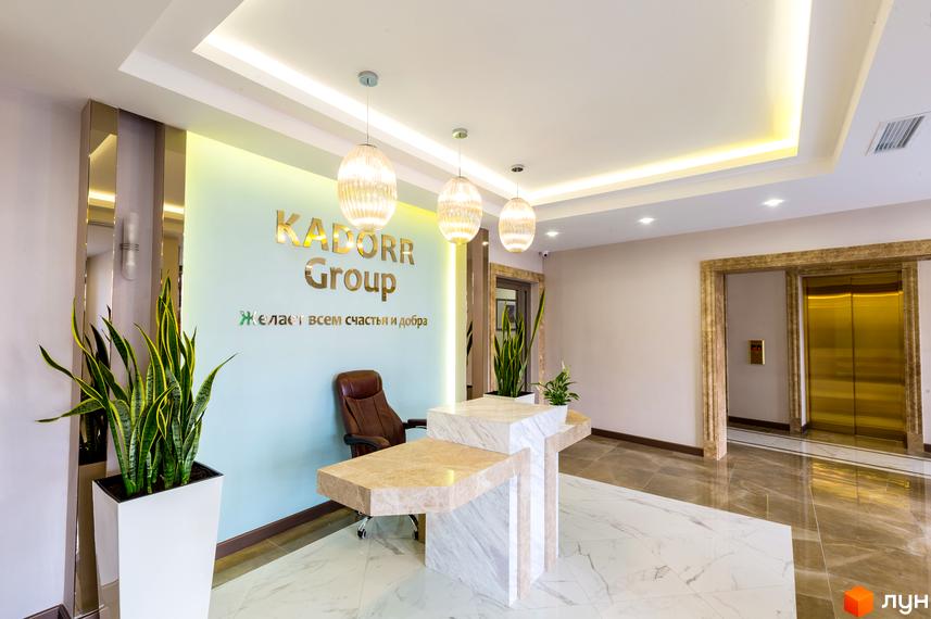 Ресепшн у Новобудові Тридцять друга перлина. Інтер'єр з меблями, рослинами та освітленням у холі житлового комплексу.