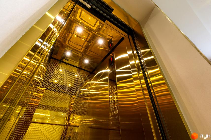Інтер'єр ліфта в Будівельному проєкті Тридцять друга перлина з золотистим оздобленням. Вигляд зсередини, панель управління з кнопками поверхів.