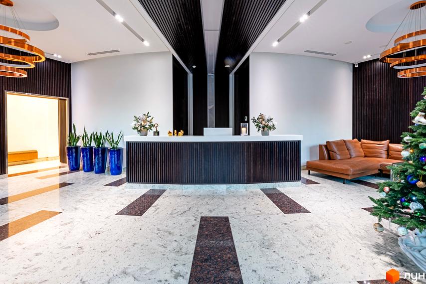 Дизайн рецепції в ЖК Skyline з диваном та новорічною ялинкою. Опис інтер'єру житлового комплексу.