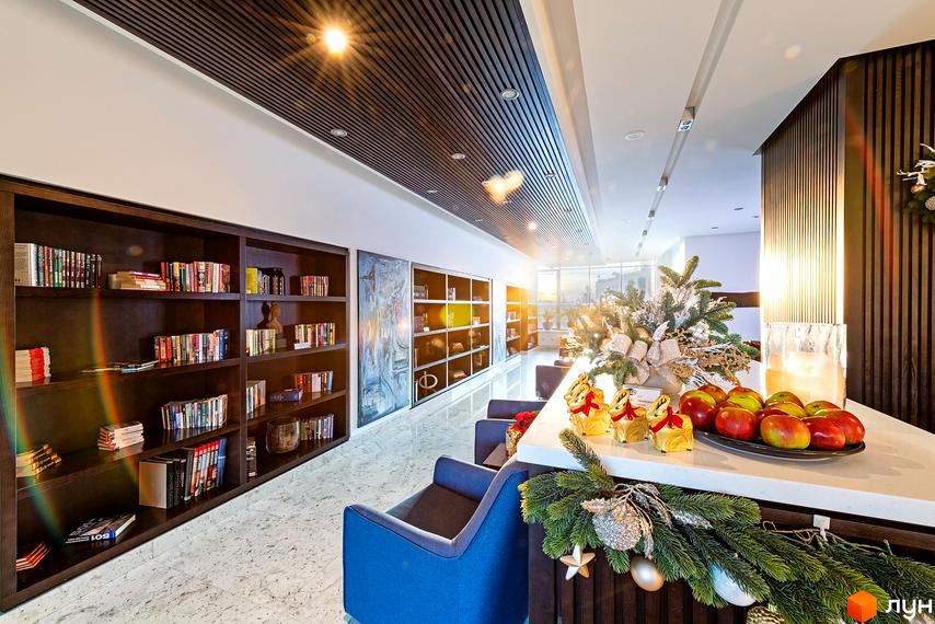 Житловий комплекс Skyline. Просторий хол з книжковими полицями, зручними кріслами та святковим декором. Ідеальне місце для відпочинку та читання.