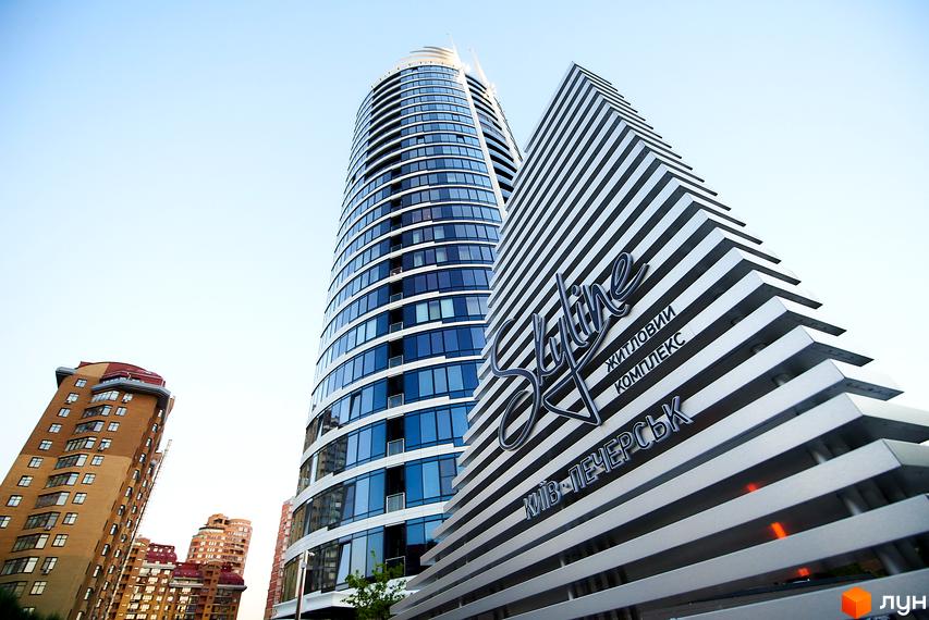 Житловий комплекс Skyline – це сучасна новобудова з вигнутим фасадом та скляним оздобленням. Поруч розташовані інші багатоповерхові будівлі.