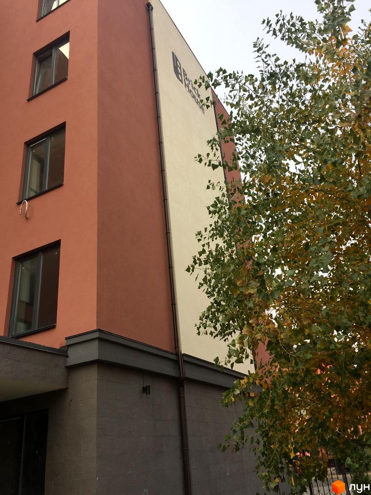 Зовнішній вигляд будівлі Клубний будинок Brick House. Фасад пофарбовано у теракотовий та кремовий кольори. Поряд росте дерево.