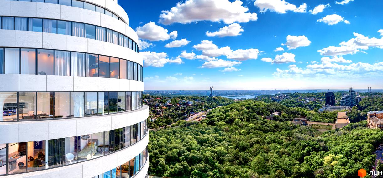 Вид на БФК INTERGAL CITY з висоти пташиного польоту. Багатоповерховий будинок з панорамними вікнами на тлі зелених насаджень та блакитного неба.