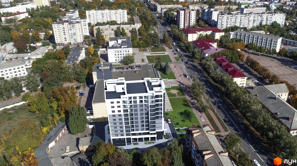 Житловий комплекс на вул. Мазепи, 23: багатоповерховий будинок з біло-сірим фасадом, оточений зеленими насадженнями та дорогою.