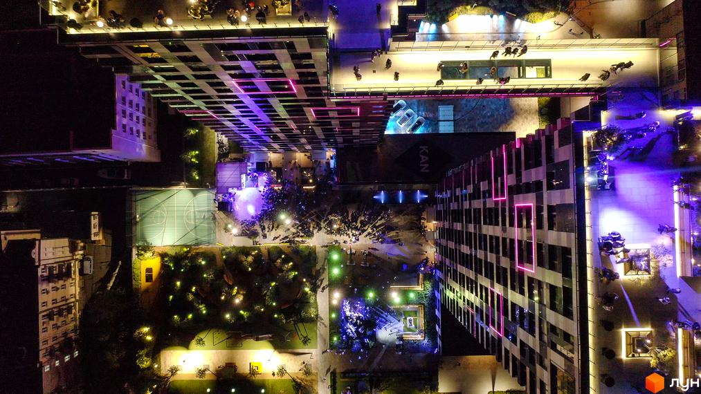 Нічний вигляд житлового комплексу Tetris Hall з висоти пташиного польоту. Освітлені фасади будівель та прибудинкова територія з баскетбольним майданчиком та зонами відпочинку.