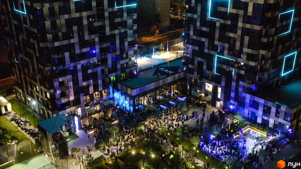 Житловий комплекс Tetris Hall з унікальним фасадом та неоновими елементами вночі. Простора прибудинкова територія з місцями для відпочинку та великою кількістю людей.
