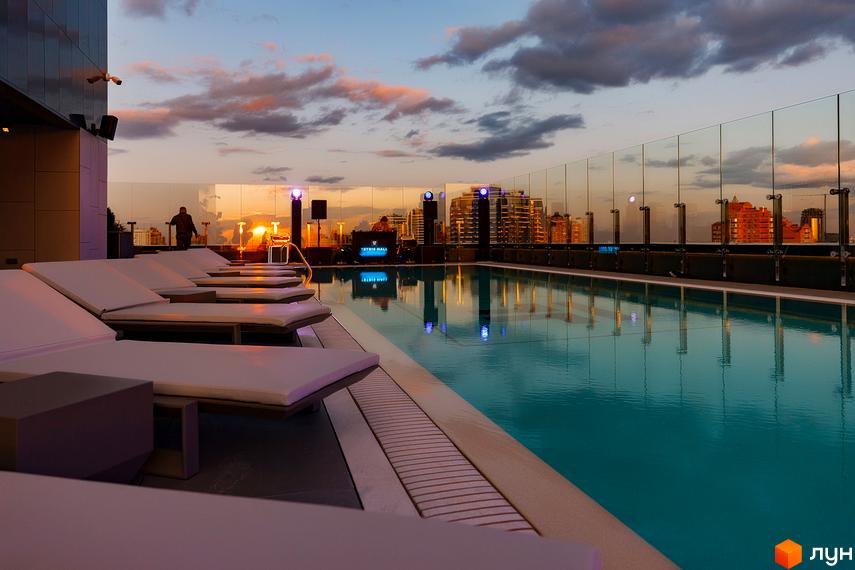 Житловий комплекс Tetris Hall з басейном на даху на заході сонця. Відпочинок та краєвиди міста.