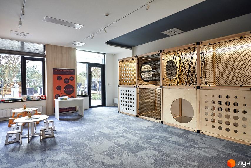 Дитяча ігрова зона в ЖК Tetris Hall з дерев'яними кубами та сітками. Простір для розвитку дітей з навчальними столами та стільцями.