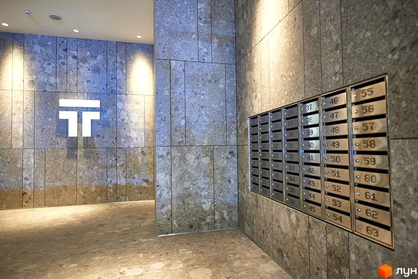 Лобі житлового комплексу Tetris Hall з фірмовим логотипом та поштовими скриньками. Сучасний дизайн інтер'єру з оздобленням стін під мармур.