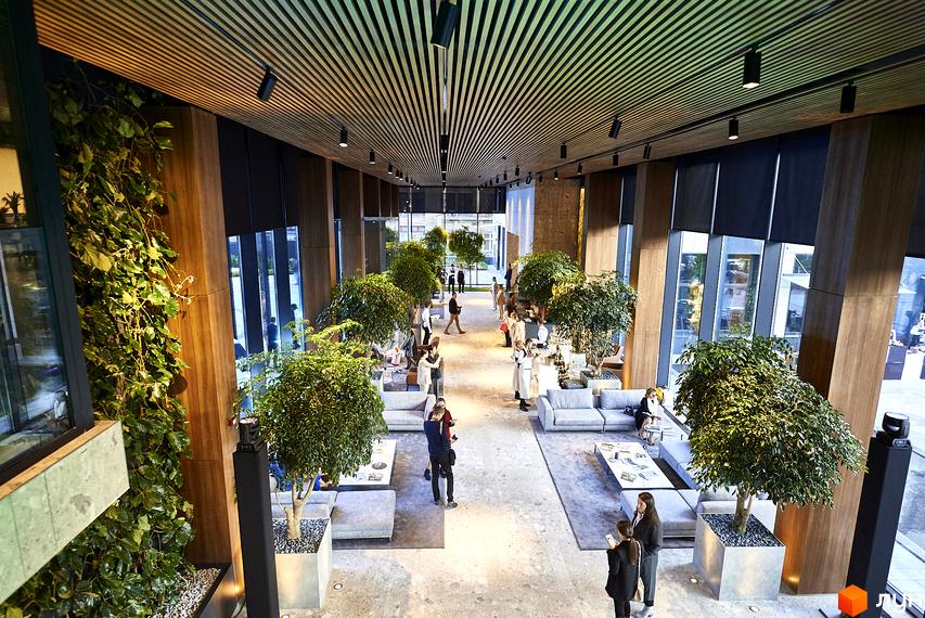 Інтер'єр лобі житлового комплексу Tetris Hall з зеленими рослинами, диванами та людьми. Просторий хол з дерев'яними елементами та великими вікнами.