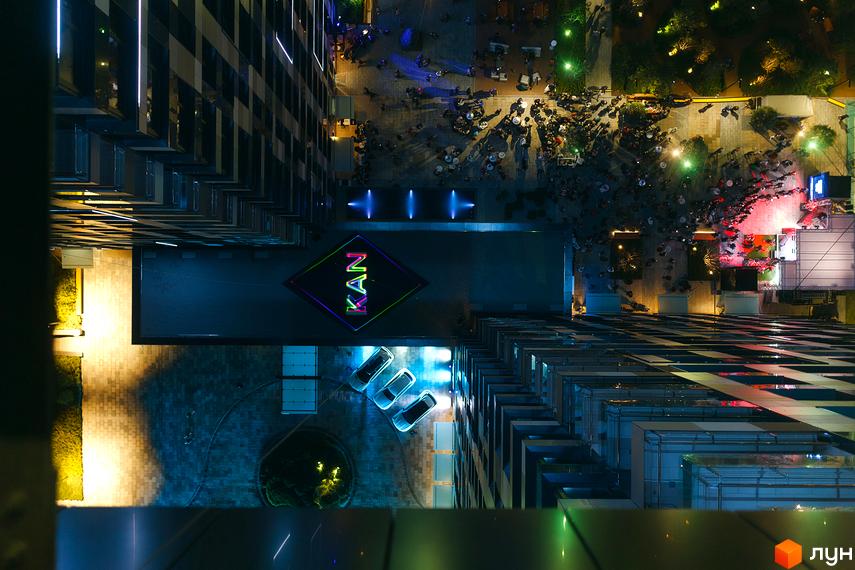 Вид зверху на житловий комплекс Tetris Hall з підсвіченою назвою та людьми на території. Оцініть сучасну архітектуру та благоустрій прибудинкової території.