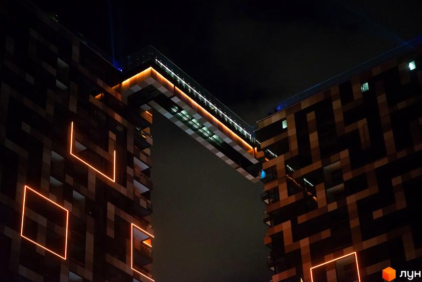 Житловий комплекс Tetris Hall у Києві. Фасади будівель прикрашені геометричними візерунками та неоновим підсвічуванням, що створює унікальний вигляд у нічний час.