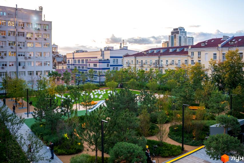 Житловий комплекс Tetris Hall з фасадами з панорамними вікнами та зеленою прибудинковою територією з зонами відпочинку та дитячим майданчиком.