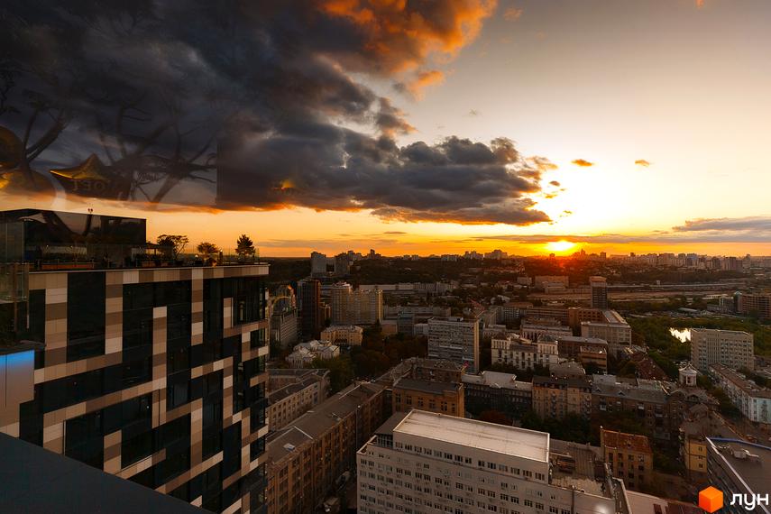 Вид на житловий комплекс Tetris Hall з висоти пташиного польоту на заході сонця. Сучасна архітектура будівлі з геометричним фасадом та зеленою зоною на даху.