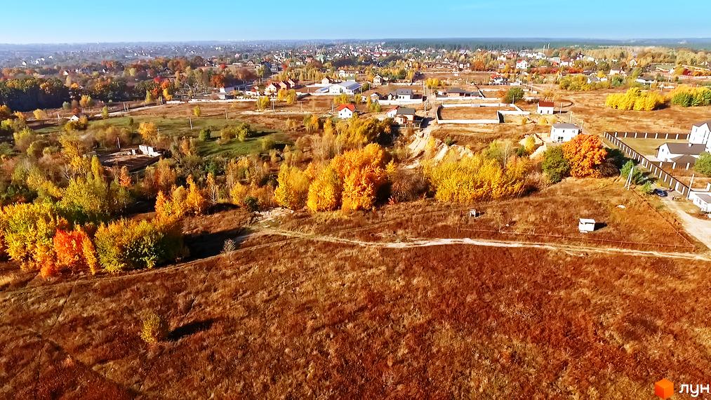 Котеджне містечко Панорама з осінніми деревами та мальовничими краєвидами. На території комплексу розташовані сучасні будинки та доглянута прибудинкова територія.