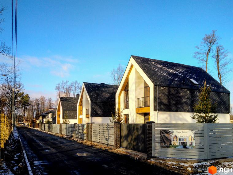 Сучасні будинки КМ Loft City з панорамними вікнами та темним дахом. Прибудинкова територія з огорожею та дорогою.