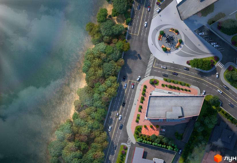 Вид зверху на житловий комплекс Берег Дніпра з прилеглою зеленою зоною та дорогою. На зображенні видно будівлю та облаштовану прибудинкову територію з деревами та доріжками.
