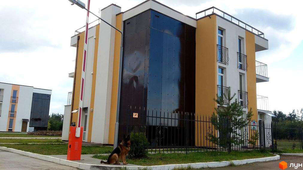 Зображення фасаду будинку в Житловому комплексі Ясний. На передньому плані видно доглянуту прибудинкову територію.