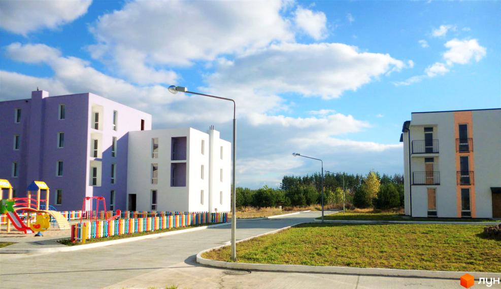 Зображення фасаду та дитячого майданчика Житлового комплексу Ясний. На фото видно багатоповерхові будинки та облаштовану прибудинкову територію.