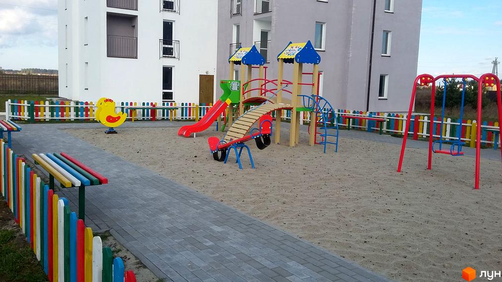 Зображення дитячого майданчика біля житлового комплексу Ясний. На фото видно гірки, гойдалки та пісочницю на території ЖК.