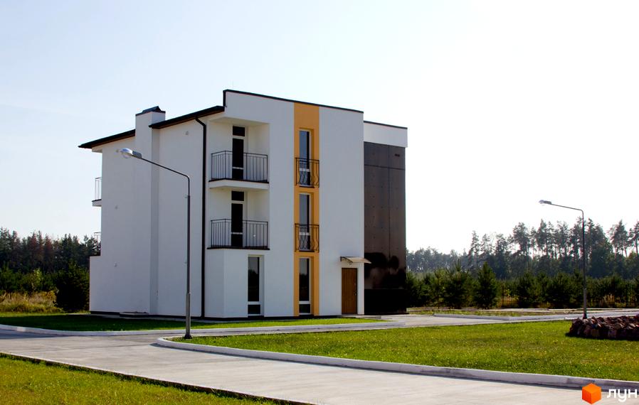 Зовнішній вигляд триповерхового будинку в Житловому комплексі Ясний з балконами. Навколо будівлі зелена галявина та асфальтована дорога.