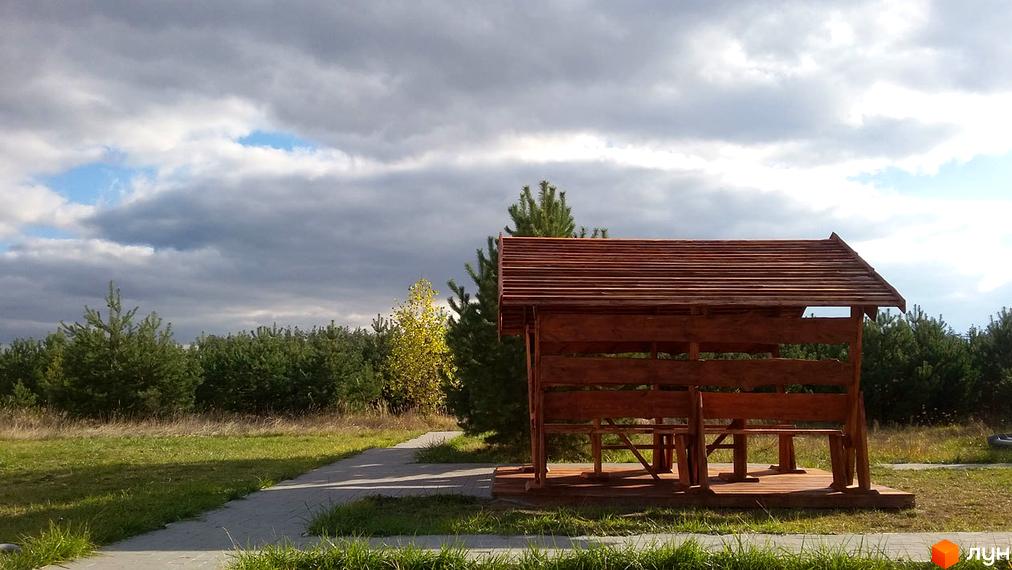 Альтанка з дерева на території Житлового комплексу Ясний. Ландшафтний дизайн з деревами та травою.