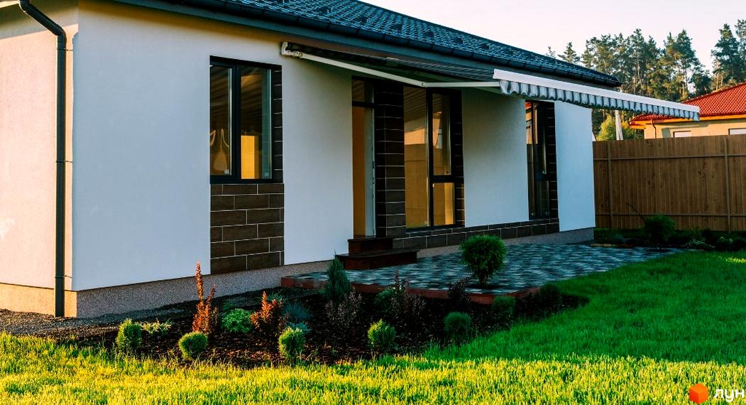 Котеджне містечко КМ Villa Grace: фасад будинку з великими вікнами та терасою, упорядкована прибудинкова територія з газоном та зеленими насадженнями.