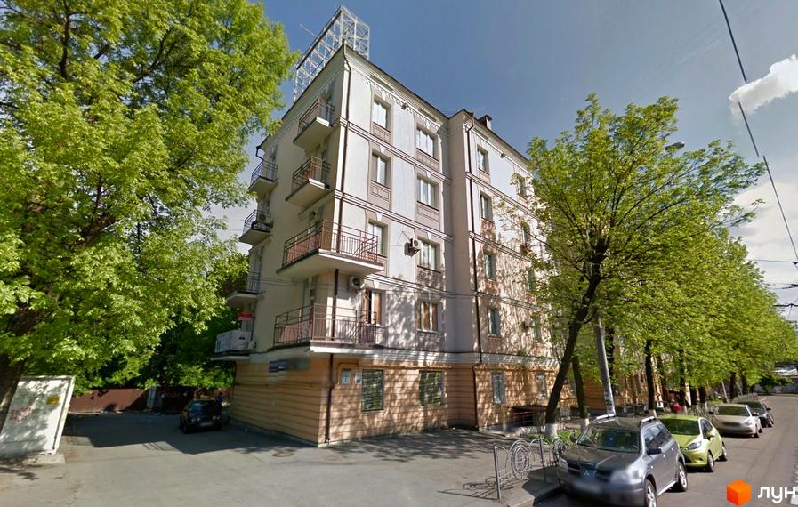 Будинок по вулиці Довженка, 2, з балконами та кондиціонерами, оточений зеленими деревами. На прибудинковій території припарковані автомобілі.