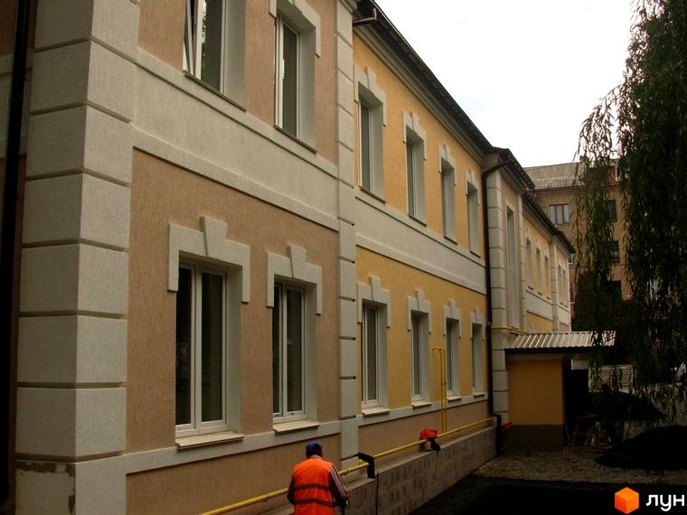 Фасад будинку за адресою пров. Керамічний, 7, з білими вікнами та декоративними елементами. Поруч видно дерева та частину прибудинкової території.