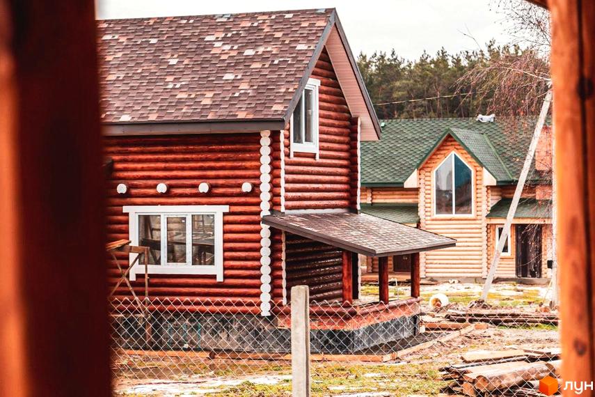 Котеджне містечко КМ Святобор: двоповерхові будинки з дерев'яного зрубу з коричневими та зеленими дахами, огороджена територія.