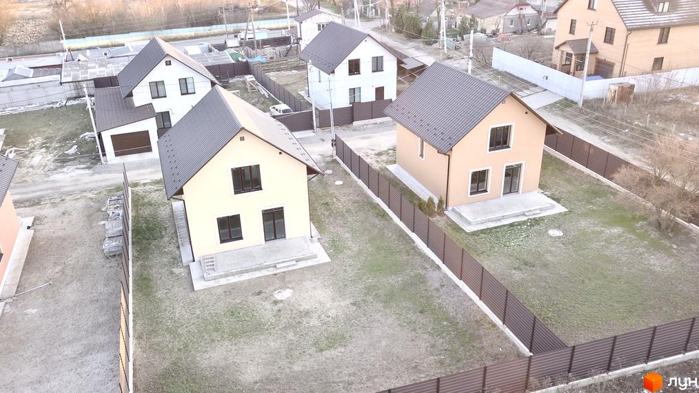 Котеджне містечко КМ Green House. Зовнішній вигляд будинків з сірими дахами та світлими фасадами, огороджена територія з газоном.