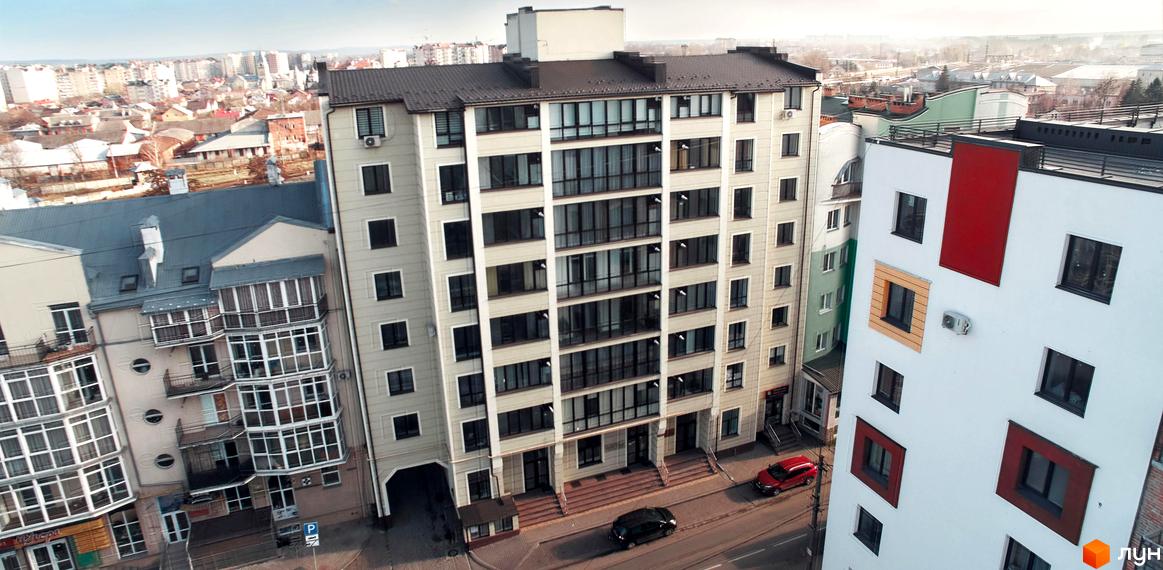 Зовнішній вигляд новобудови на вул. Залізнична, 4. Багатоповерховий будинок з великою кількістю вікон та балконів, розташований у міському середовищі.